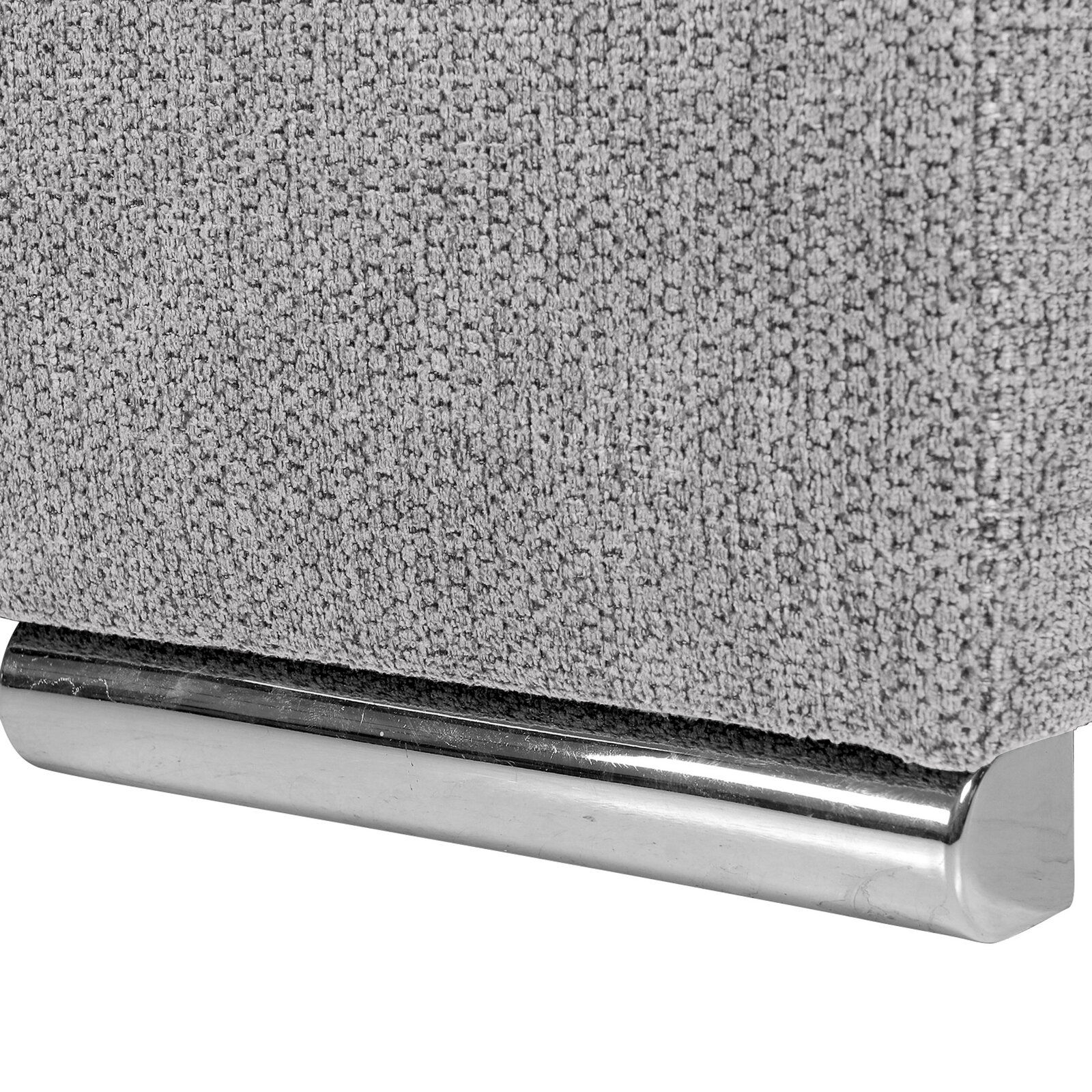 Nahaufnahme einer grauen, texturierten Stoffoberfläche mit einem glänzenden, metallischen Fuß. Perspektive von der Seite.