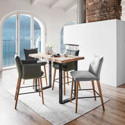 Moderner Bartisch mit Holzplatte und schwarzen Metallbeinen, umgeben von stilvollen Barhockern in einem hellen Raum mit Blick auf einen See. Perspektive: seitlich.