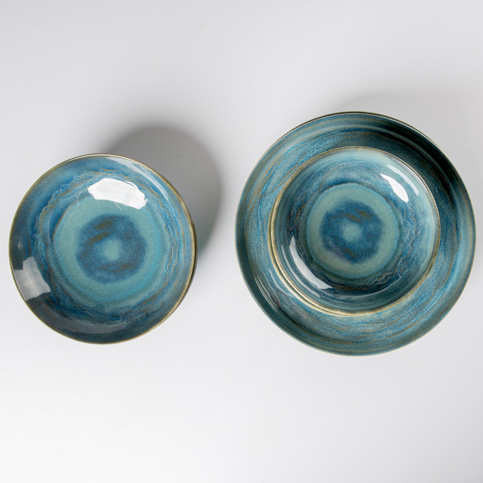 Draufsicht auf zwei glasierte Keramik-Schalen/Teller in Blau-Türkis mit konzentrischem Ringmuster auf weißem Hintergrund, links kleiner, rechts größer