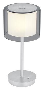 Moderne LED-Tischleuchte KLARA mit zylindrischem, transparentem Schirm und silbernem Standfuß, seitliche Perspektive.