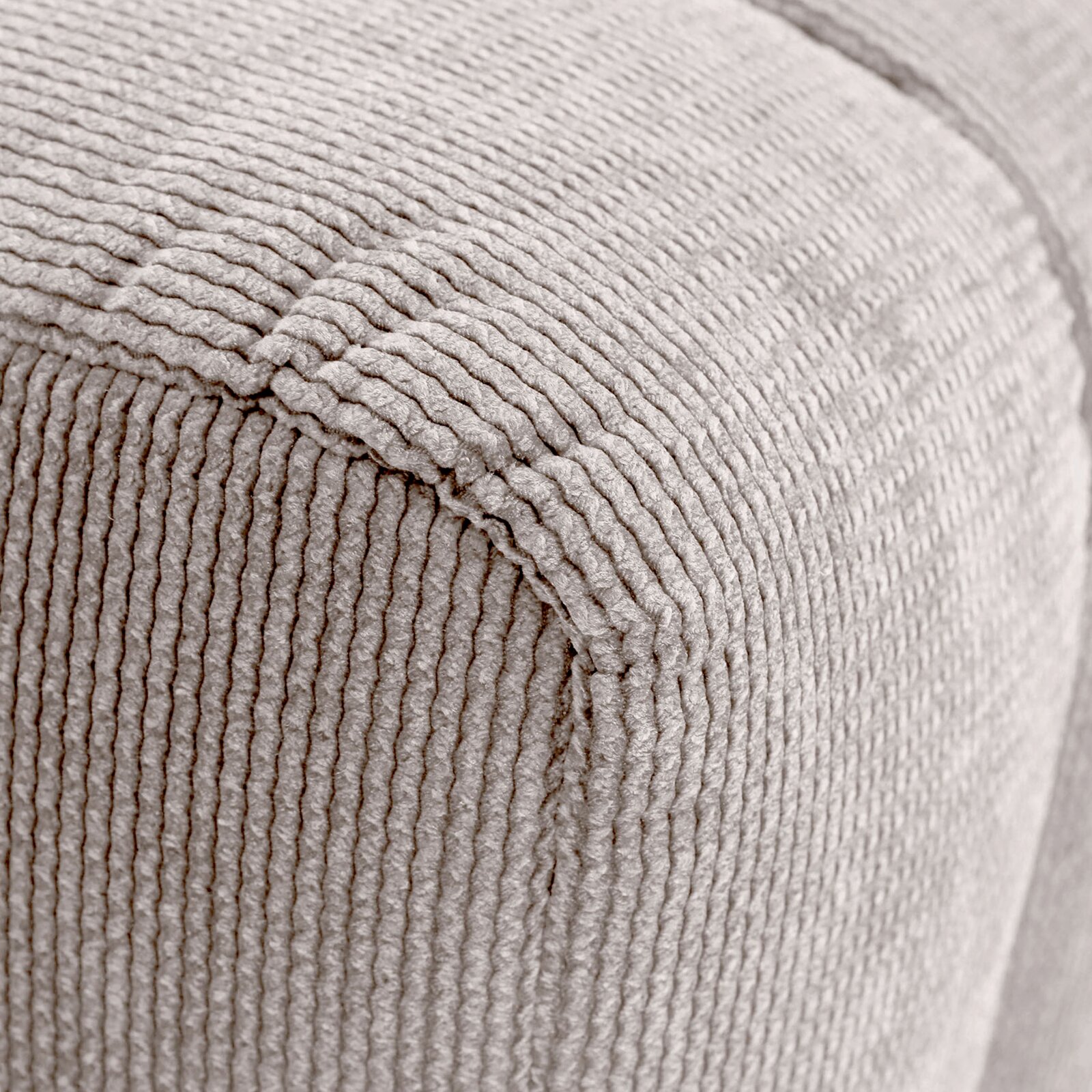 Nahaufnahme eines Hockers mit beige geripptem Stoffbezug, perspektivisch von der Ecke aufgenommen.