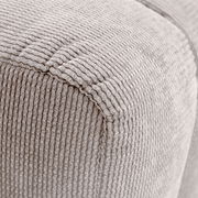 Nahaufnahme eines Hockers mit beige geripptem Stoffbezug, perspektivisch von der Ecke aufgenommen.