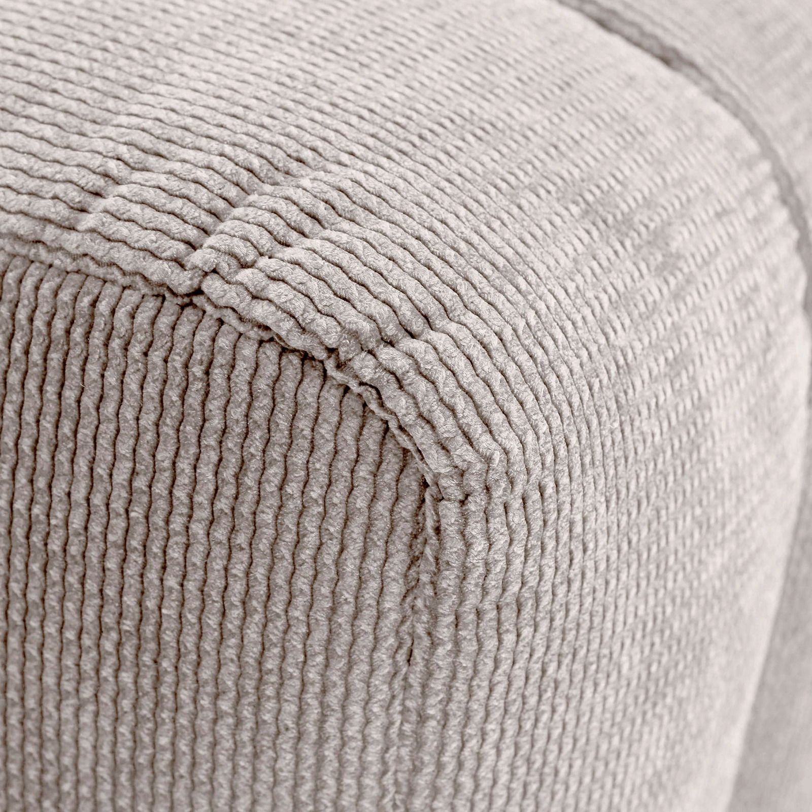 Nahaufnahme eines Hockers mit beige geripptem Stoffbezug, perspektivisch von der Ecke aufgenommen.
