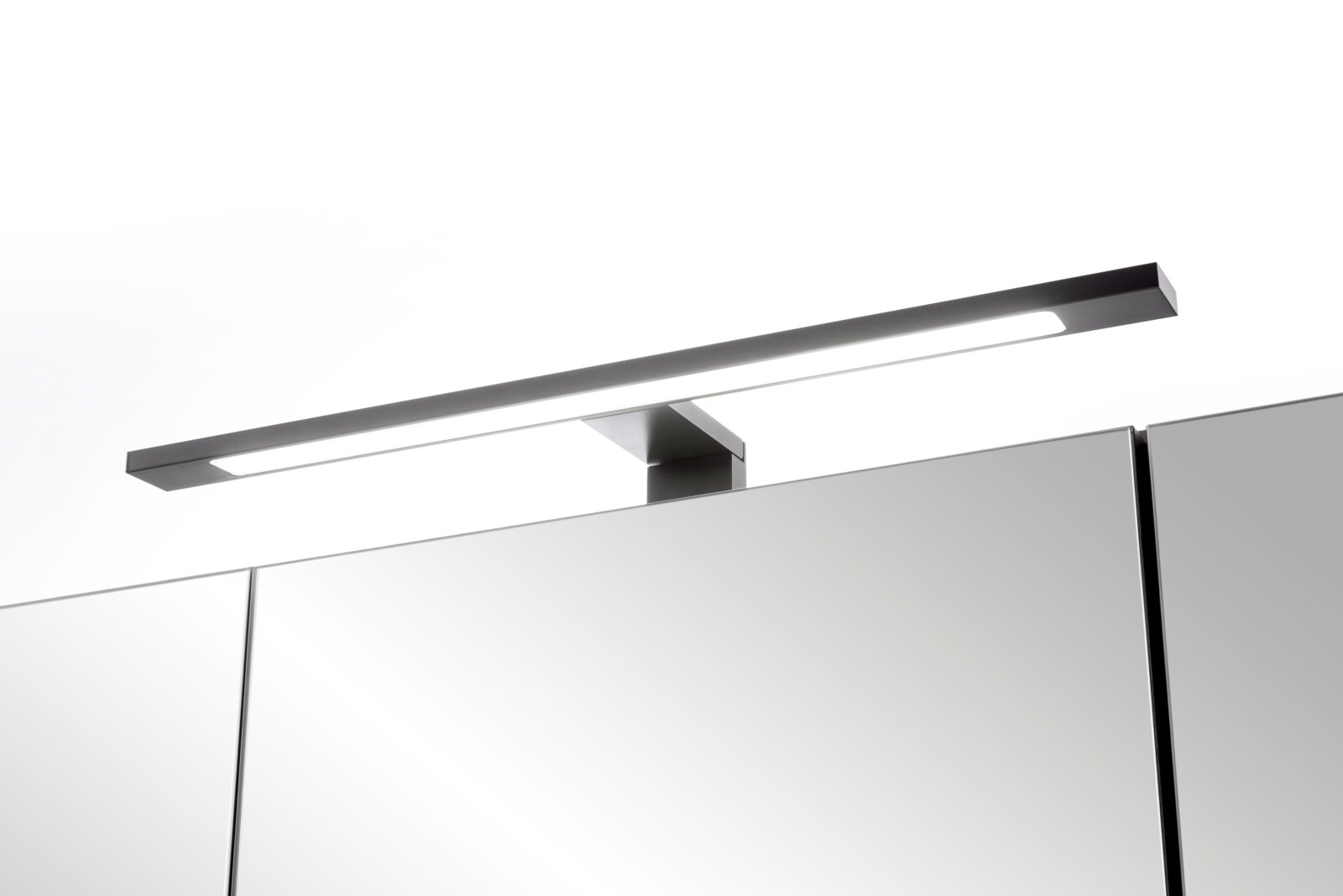 Schlanke LED-Spiegelleuchte in gebürsteter Edelstahl-Optik auf einem Badezimmerspiegelschrank, schräg von vorne oben fotografiert