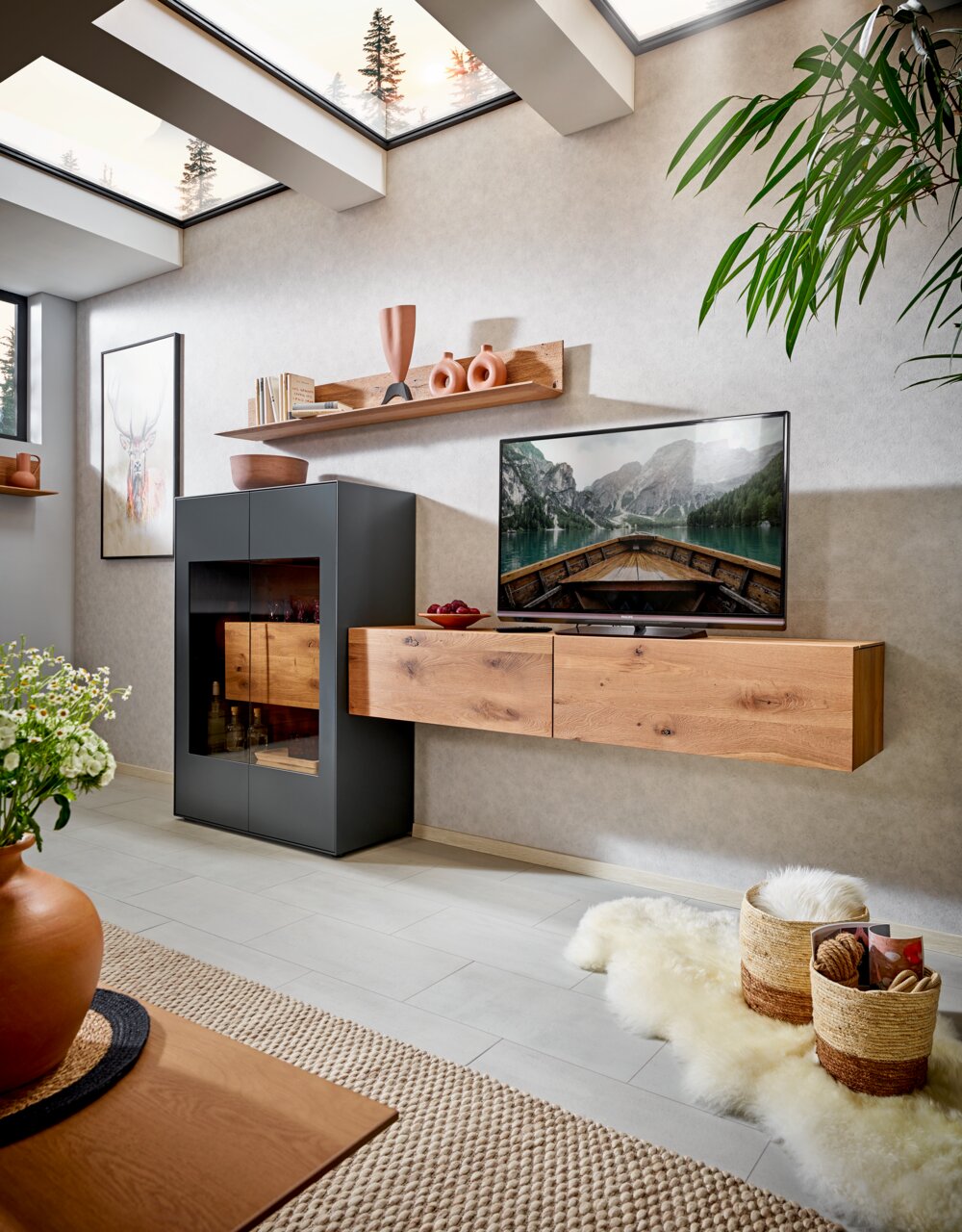 Valnatura Wandcombinatie LIVINO Moderne wandcombinatie voor de woonkamer met een houten kast en plank, versierd met vazen en boeken, gezien vanuit een gezellige woonkamer met helder daglicht.