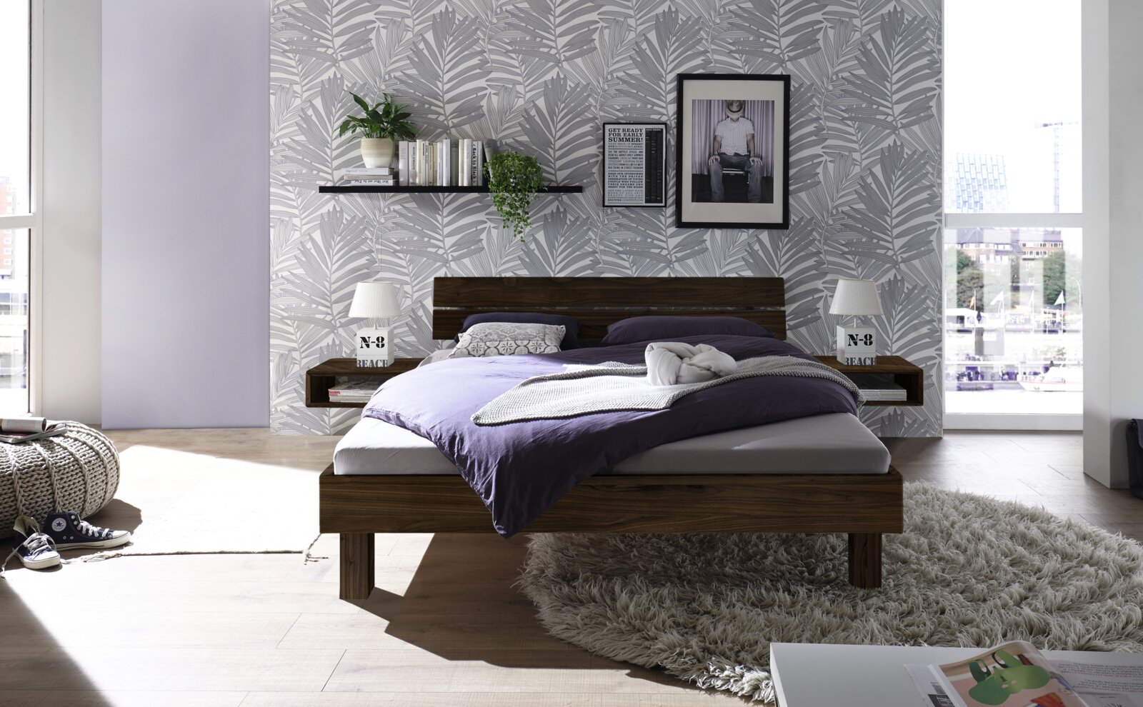Modernes Schlafzimmer mit einem Kopfteil aus Holz und Metall, frontal fotografiert. Das Bett ist mit lila und weißen Bettwaren dekoriert, umgeben von stilvollen Nachttischen und einer gemütlichen Atmosphäre.