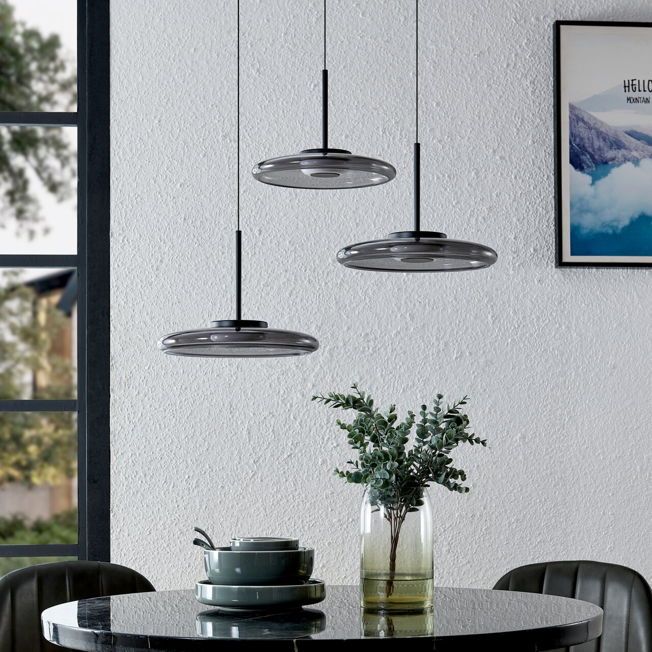 Moderne LED-Hängeleuchte in dreifacher Ausführung über einem Esstisch, seitliche Perspektive