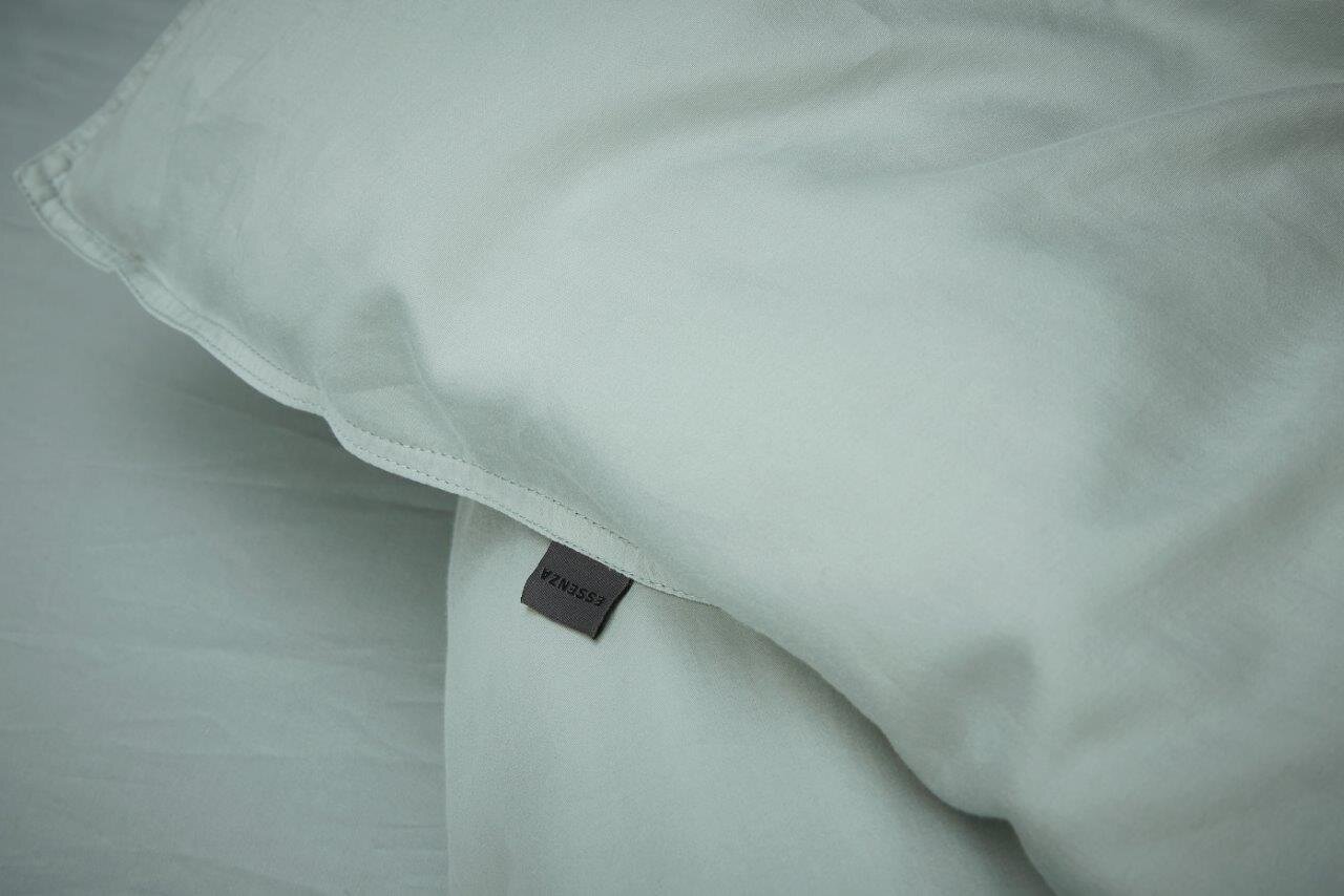 Nahaufnahme einer hellgrauen Bettwäsche mit sichtbarem Etikett, Perspektive von oben.
