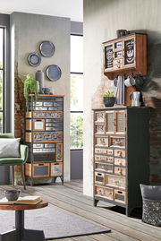 Hochkommode im industriellen Stil mit verschiedenen Schubladen und Mustern, fotografiert aus einer leicht seitlichen Perspektive.