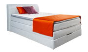 Boxspringbett in seitlicher Perspektive mit grauem Stoffbezug, zwei Kissen in Orange und Lila sowie einer orangefarbenen Decke.