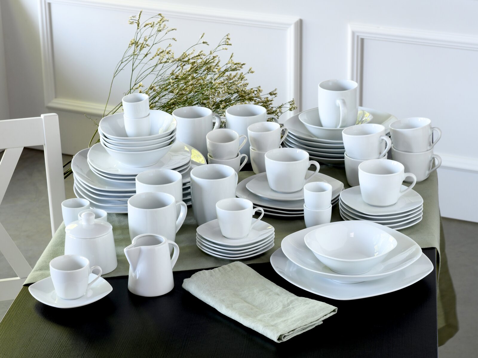Creatable Kombiservice 62-tlg SQUARE Weißes Porzellan-Geschirrset mit Tellern, Schalen, Tassen, Kanne und Milchkännchen auf gedecktem Tisch, aufgenommen in schräger Perspektive von vorn oben.
