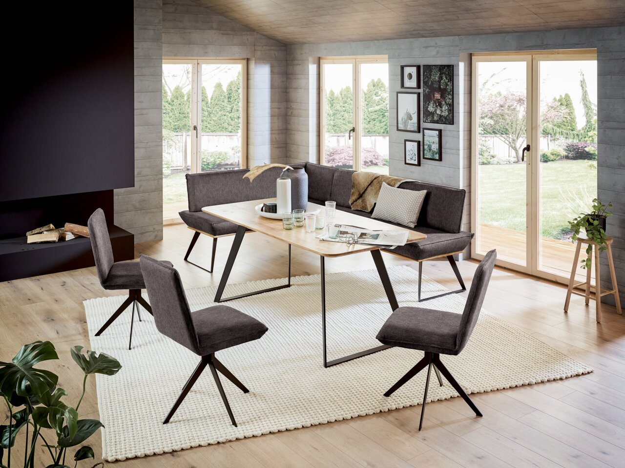 Moderne Esszimmer-Eckbank mit Esstisch und Stühlen in einem hellen Raum mit großen Fenstern, seitliche Perspektive.