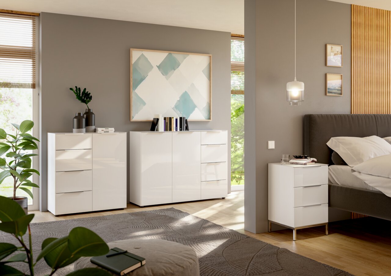 Moderne weiße Hochglanz-Kommoden und Nachttisch in einem stilvollen Schlafzimmer, seitliche Perspektive.