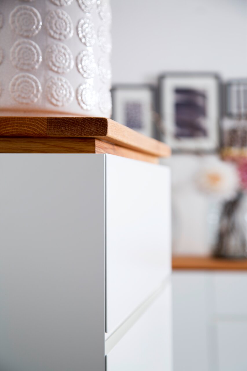 Nahaufnahme eines weißen Möbelstücks mit Holzplatte, seitliche Perspektive