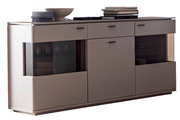 Modernes Sideboard in Grau mit abgerundeten Ecken, zwei getönten Glas-Schiebetüren und Schubladen, mit Deko auf der Deckplatte, in frontaler Ansicht leicht von links fotografiert.