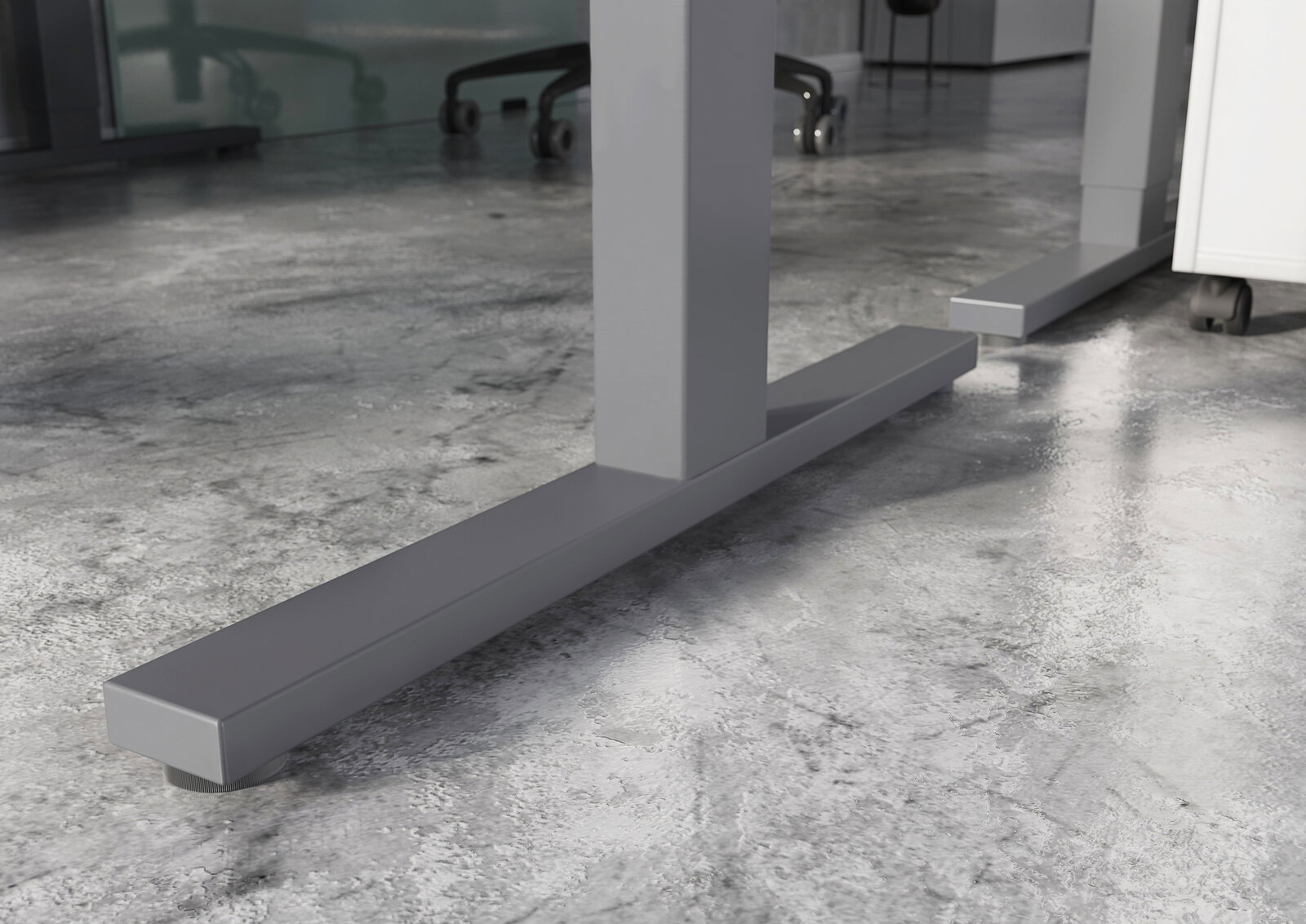 Nahaufnahme der stabilen Metallfüße eines E-Schreibtisches auf einem Betonboden, seitliche Perspektive.
