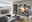 Moderne Wohnzimmer-Wandkombination in grauer Farbe mit Holzakzenten, bestehend aus TV-Schrank, Vitrine und Hängeregalen, in einem stilvoll eingerichteten Raum mit Blick auf die Stadt aus der Fensterperspektive.
