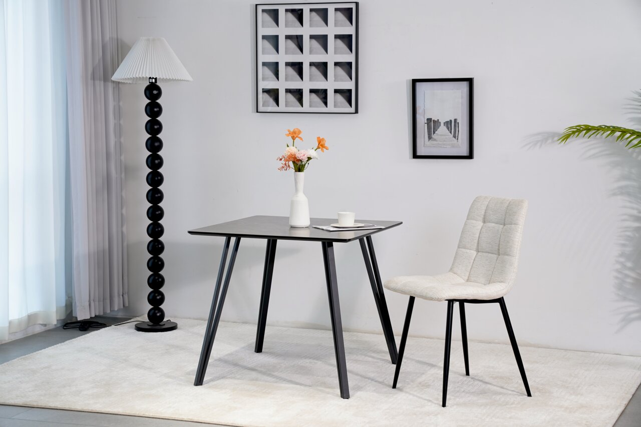 Z2 Esstisch HILMAR Moderner Esstisch mit schwarzer Tischplatte und schrägen Beinen, seitliche Perspektive, dekoriert mit einer Vase und Blumen.