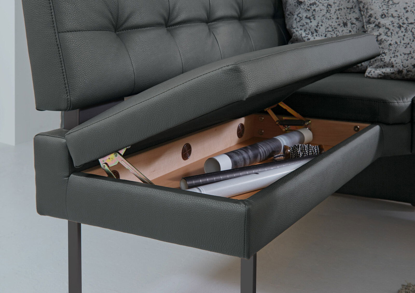 Nahaufnahme einer Eckbank mit aufklappbarem Sitzpolster, das Stauraum für Gegenstände bietet.