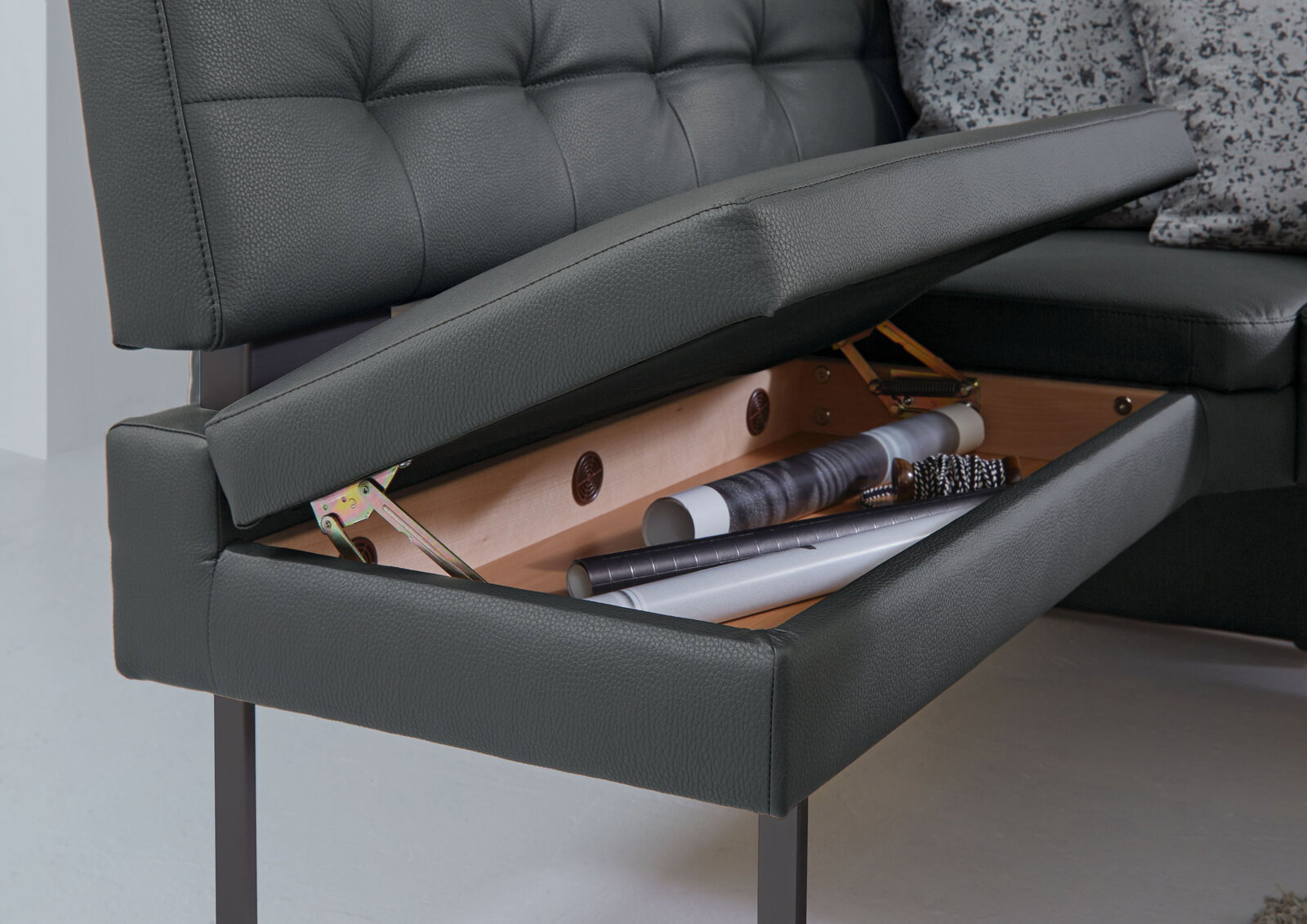 Nahaufnahme einer Eckbank mit aufklappbarem Sitzpolster, das Stauraum für Gegenstände bietet.