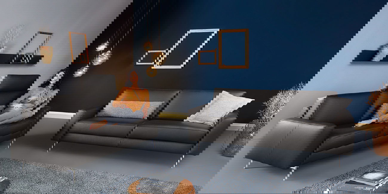 Modernes Wohnzimmer mit zwei dunklen Sofas und blauen Wänden.