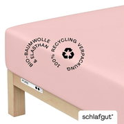 Roze hoeslaken van biologisch katoen en elastaan, gespannen over een matras, met vermelding van 100% gerecyclede verpakking, zijaanzicht.