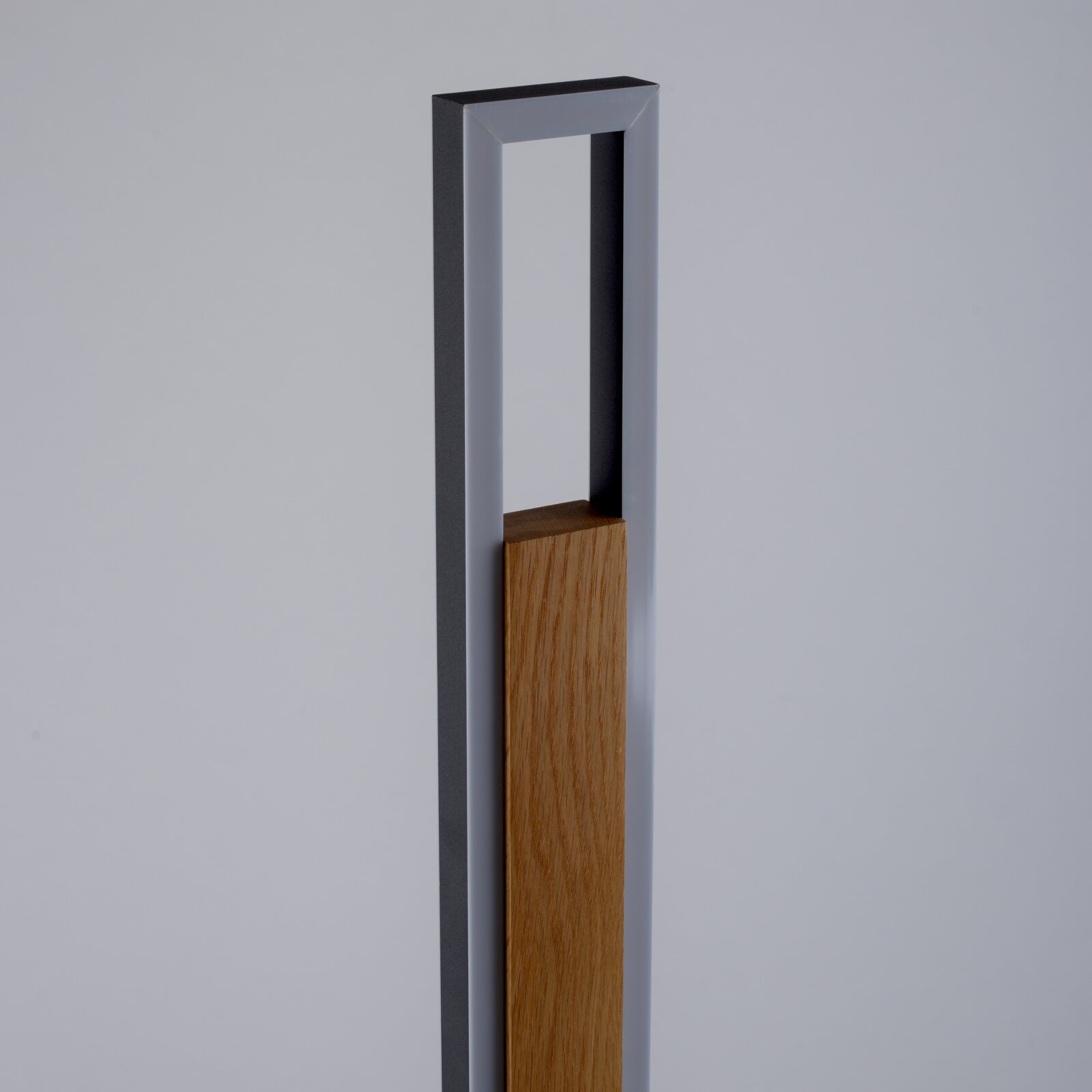 Minimalistisch hoog object met een antracietkleurig rechthoekig metalen frame en een naturel houten inzetstuk, gezien vanuit schuin vooraanzicht.