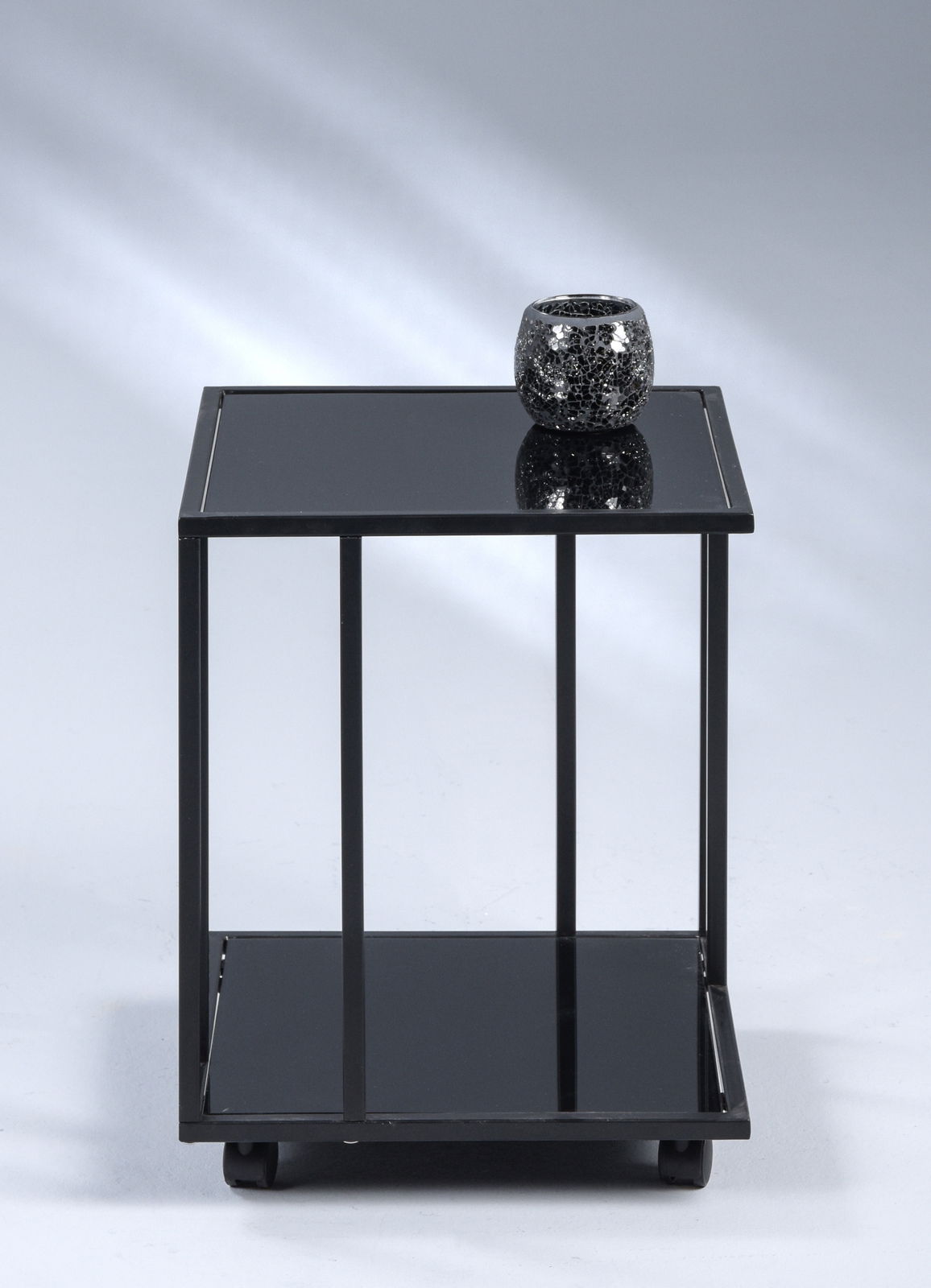 Z2 Beistelltisch PARIS Schwarzer Beistelltisch mit Glasoberfläche, darauf ein dekoratives Teelicht, frontal fotografiert.