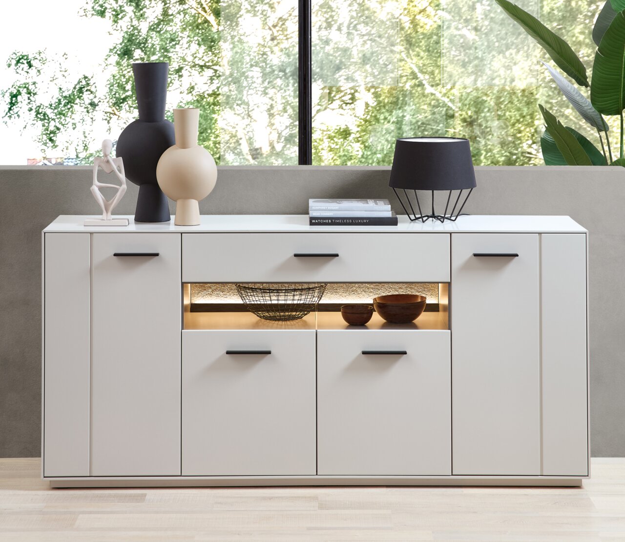 Modernes weißes Sideboard mit dekorativen Vasen und Lampe, frontal fotografiert.