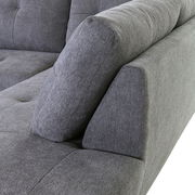 Nahaufnahme einer grauen Sofaecke mit gepolsterten Kissen, seitliche Perspektive.