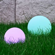Zwei kugelförmige Solarleuchten von Ambia Garden im Gras, eine in Lila und eine in Türkis, aus seitlicher Perspektive fotografiert.