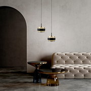 Zwei moderne LED-Pendelleuchten in einem eleganten Raum mit einem beigen Sofa und stilvollen Beistelltischen, seitliche Perspektive.