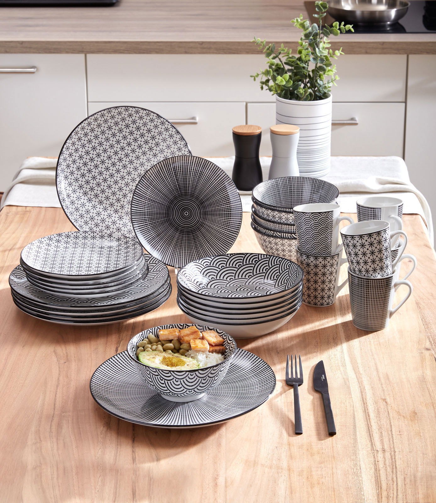 Novel Kombiservice 30-tlg. TOKYO Kombiservice Tokyo 30-teilig, schwarz-weißes Geschirrset mit geometrischen Mustern, auf einem Holztisch in einer modernen Küche präsentiert, seitliche Perspektive.