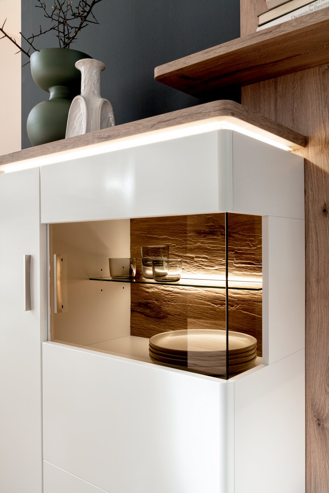 Stylife Highboard PALERMO Modernes weißes Sideboard mit beleuchtetem Glasvitrinenfach, Holzrückwand und Metallgriffen; perspektivische Nahaufnahme von schräg vorne rechts