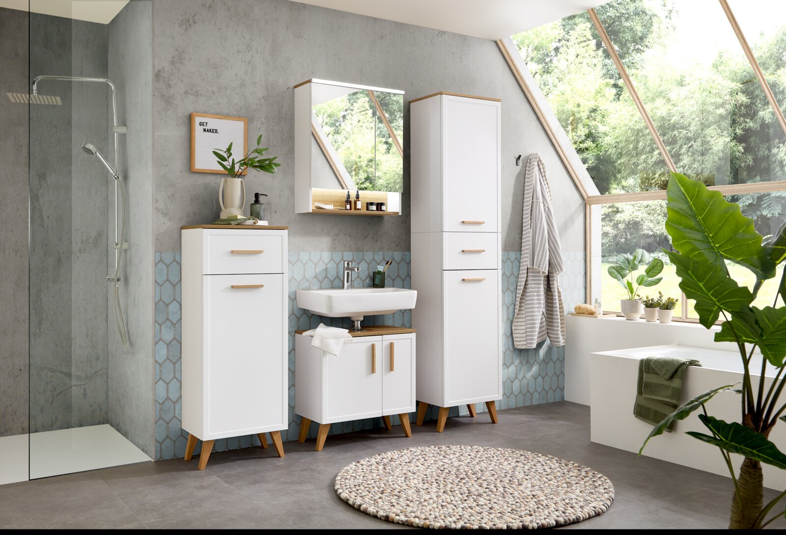 Moderner weißer Unterschrank im Badezimmer, frontal betrachtet, mit Holzdetails und eleganten Griffen, umgeben von weiteren Badmöbeln und Pflanzen.