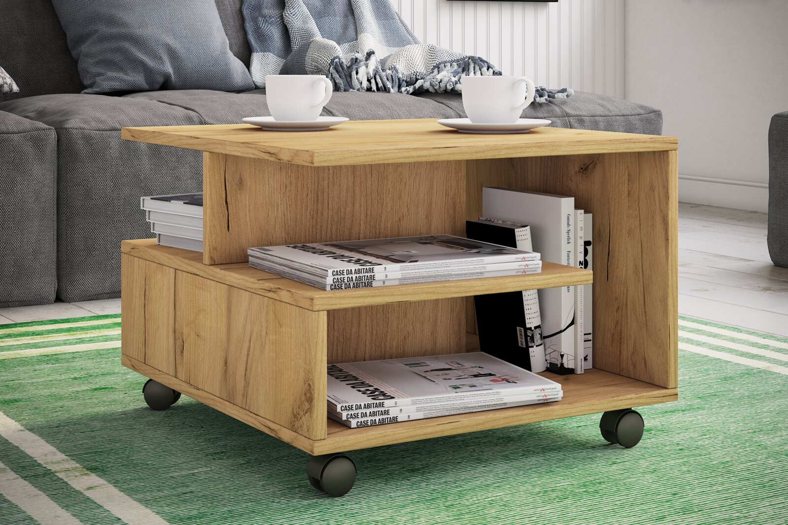 Moderner Couchtisch aus Holz in Eiche-Optik mit zwei Ablagefächern und Rollen, mit Zeitschriften und Tassen dekoriert, Perspektive: frontale 3/4-Ansicht von leicht oben im Wohnzimmer.