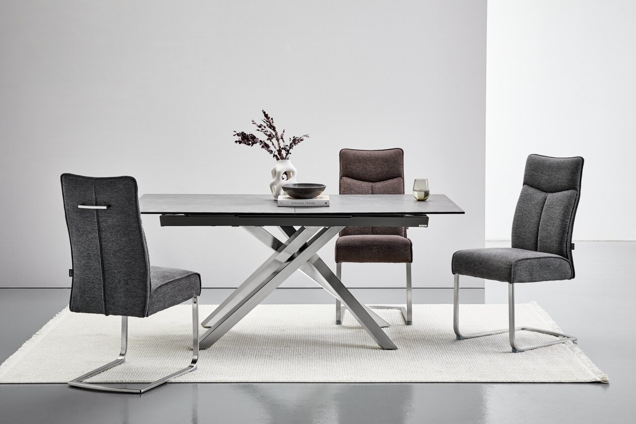 Novel Freischwinger BUFFY Moderner Essbereich mit einem rechteckigen Tisch und drei Freischwinger-Stühlen in verschiedenen Grautönen, seitliche Perspektive.