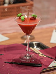 Zelfgemaakte rode kaars in een cocktailglas, versierd met decoratief fruit als origineel DIY-project.