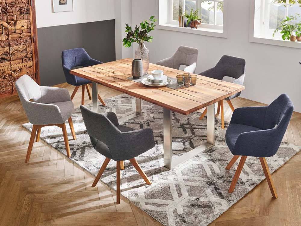 Esszimmer mit Holztisch und sechs grauen Stühlen auf einem gemusterten Teppich.