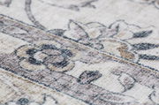 Nahaufnahme eines Teppichs mit floralem Muster in sanften Beige- und Grautönen, schräg von der Seite fotografiert.