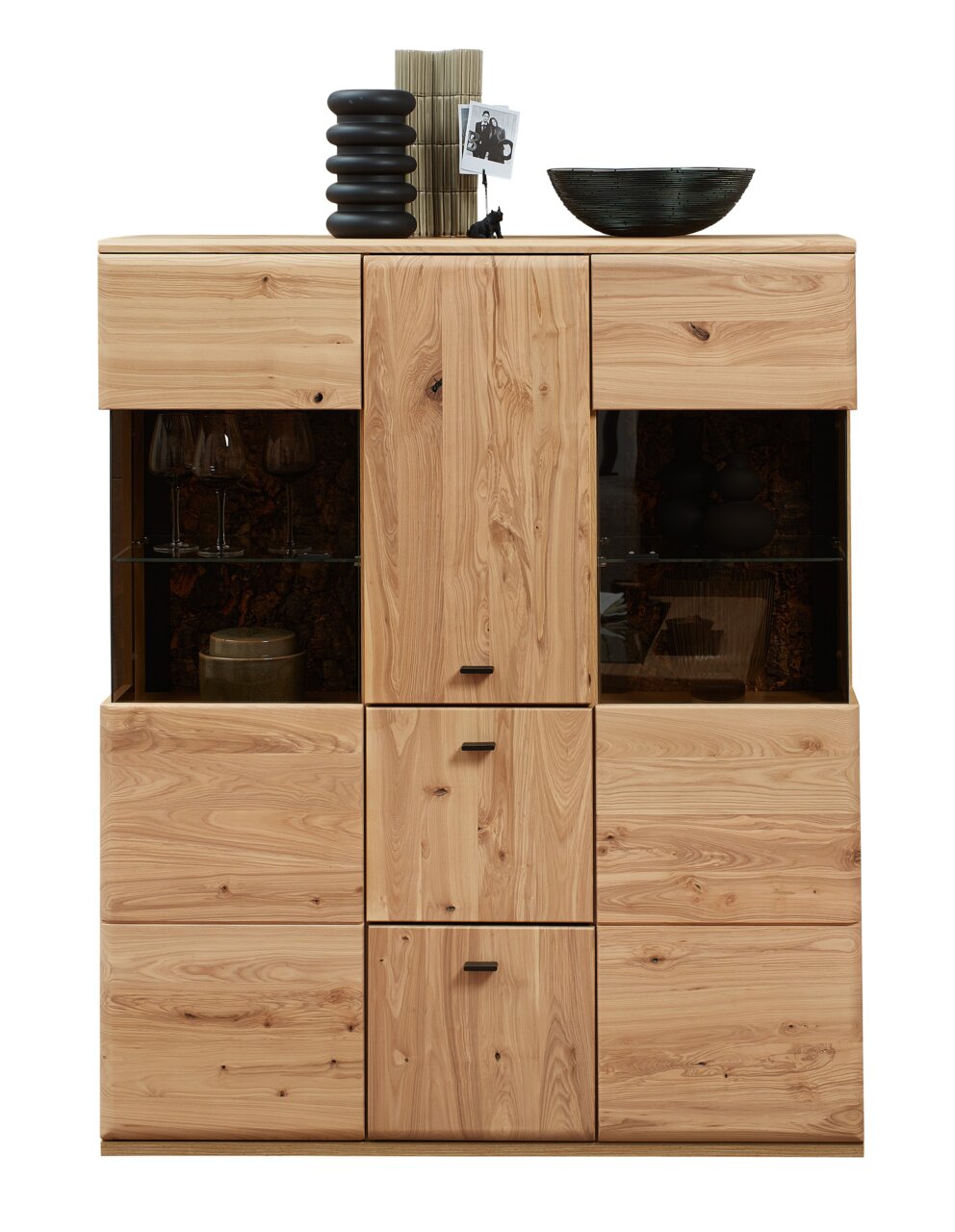 Frontale Ansicht des Highboards Linea Natura CALMERA aus Holz mit mehreren Schubladen und Fächern, dekoriert mit Vasen und einer Schale.