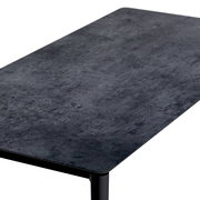 Moderner Loungetisch mit dunkler, steinartiger Oberfläche, aus schräger Perspektive fotografiert.