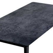 Moderne salontafel met een donker, steenachtig oppervlak, gefotografeerd vanuit een schuin perspectief.