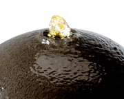 Nahaufnahme eines Brunnens aus recyceltem Kunststoff mit sprudelndem Wasser an der Spitze, von oben betrachtet.