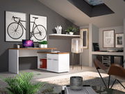 Moderner Eckschreibtisch in einem stilvollen Arbeitszimmer mit Dekorationen, Pflanzen und einem Laptop, aus der Perspektive von vorne links betrachtet.