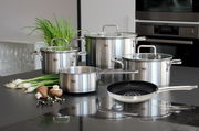 Topfset Topas 5-tlg. aus Edelstahl, bestehend aus vier Töpfen mit Glasdeckeln und einer Pfanne, auf einer Küchenarbeitsplatte präsentiert. Perspektive von vorne.