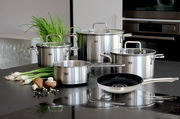Topfset Topas 5-tlg. aus Edelstahl, bestehend aus vier Töpfen mit Glasdeckeln und einer Pfanne, auf einer Küchenarbeitsplatte präsentiert. Perspektive von vorne.