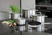 Topfset Topas 5-tlg. aus Edelstahl, bestehend aus vier Töpfen mit Glasdeckeln und einer Pfanne, auf einer Küchenarbeitsplatte präsentiert. Perspektive von vorne.
