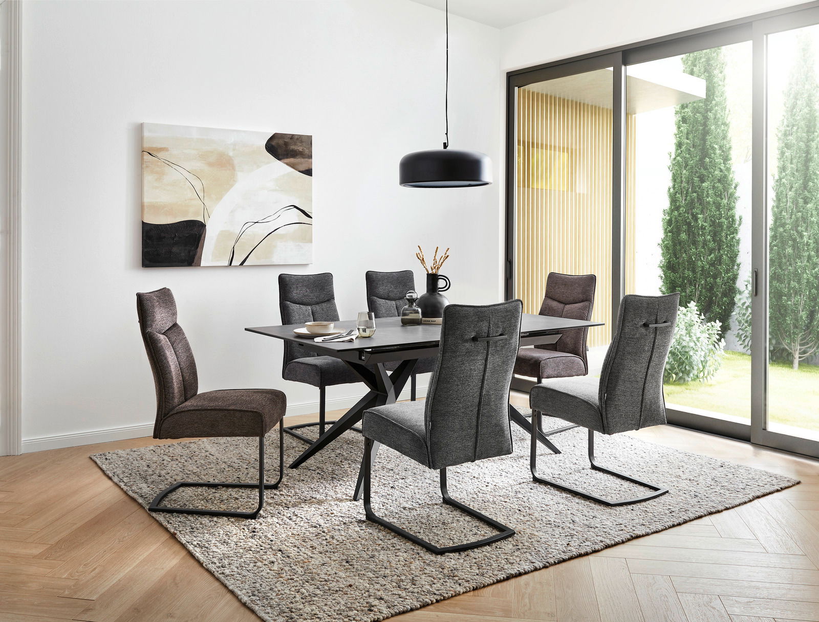 Moderner Esstisch mit sechs gepolsterten Stühlen in einem hellen Raum mit großen Fenstern, seitliche Perspektive.