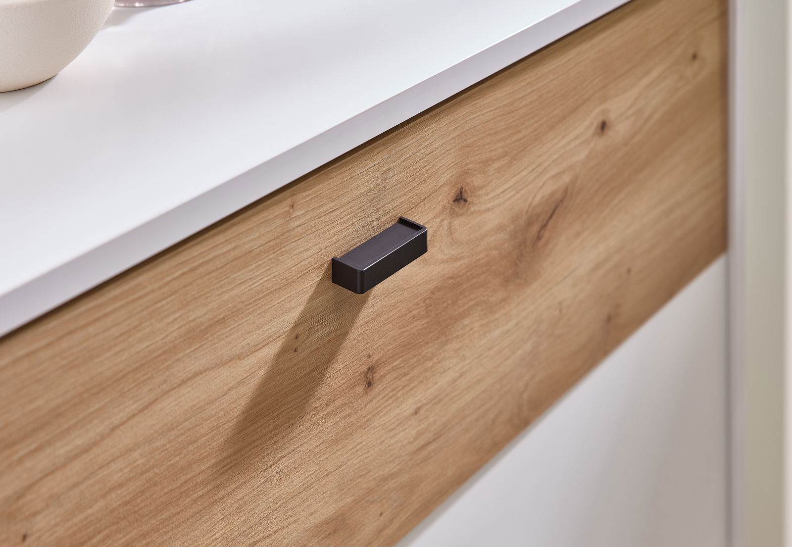 Nahaufnahme einer Kompaktgarderobe mit Holzoptik und schwarzem Griff, seitliche Perspektive